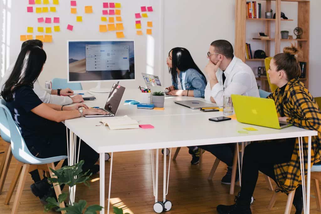 a group of people sitting around a table looking at a large computer screen