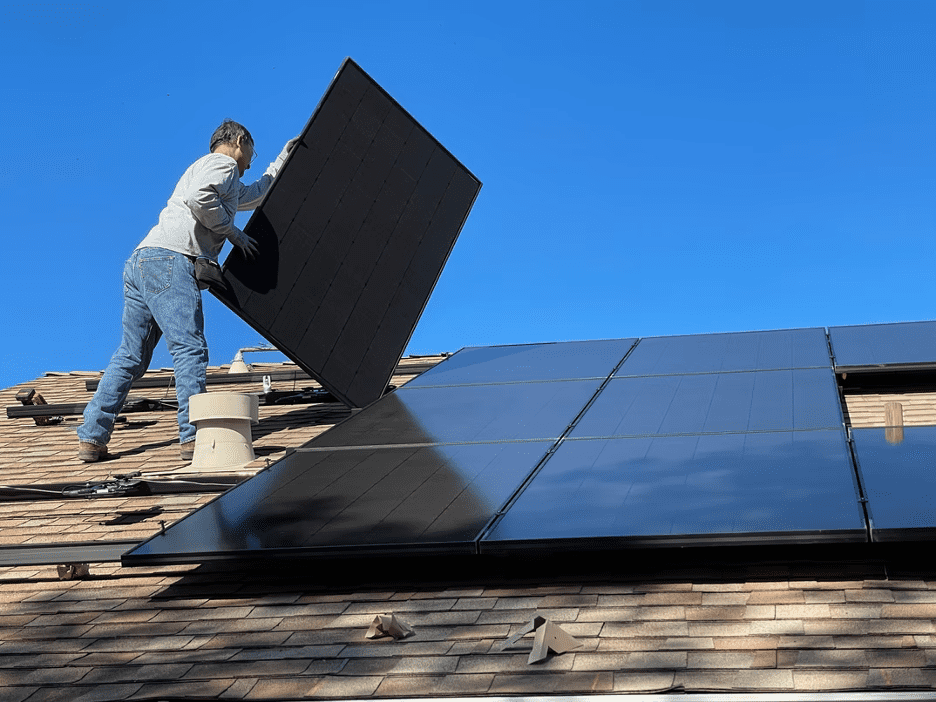 A man installing eco-friendly solar panels to his roof.