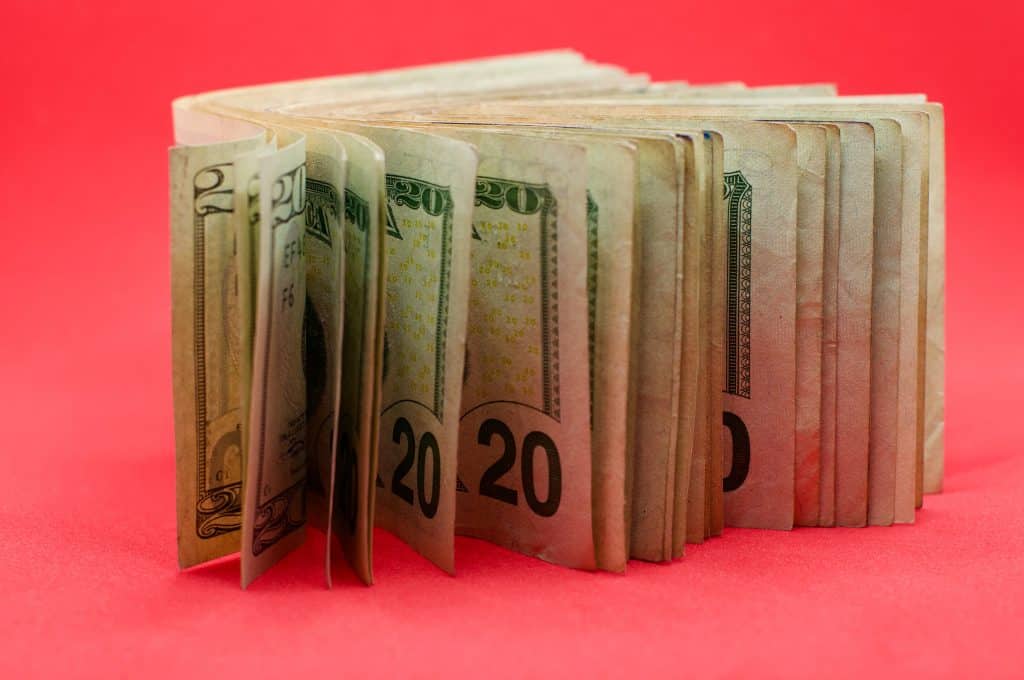 A stack of cash on a bright pink background