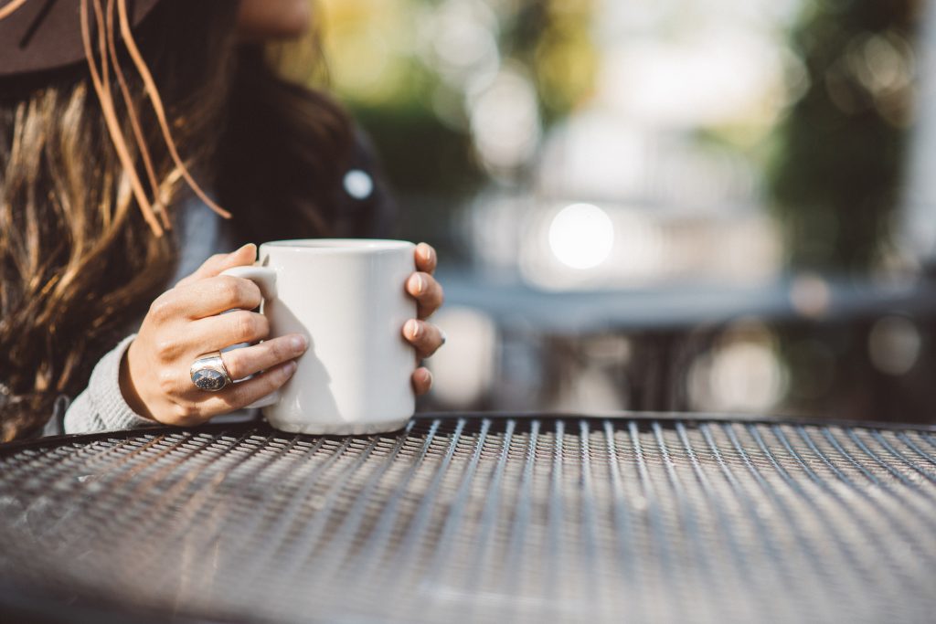 A woman drinking from a mug outside