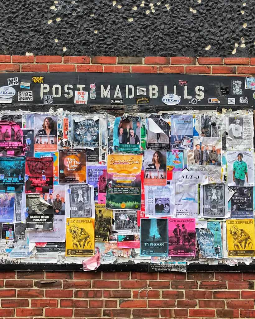 A wall of flyers hanging on brick