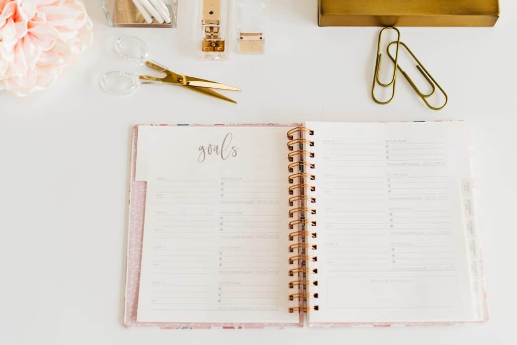 A goals journal sitting open on a table surrounded by office supplies.