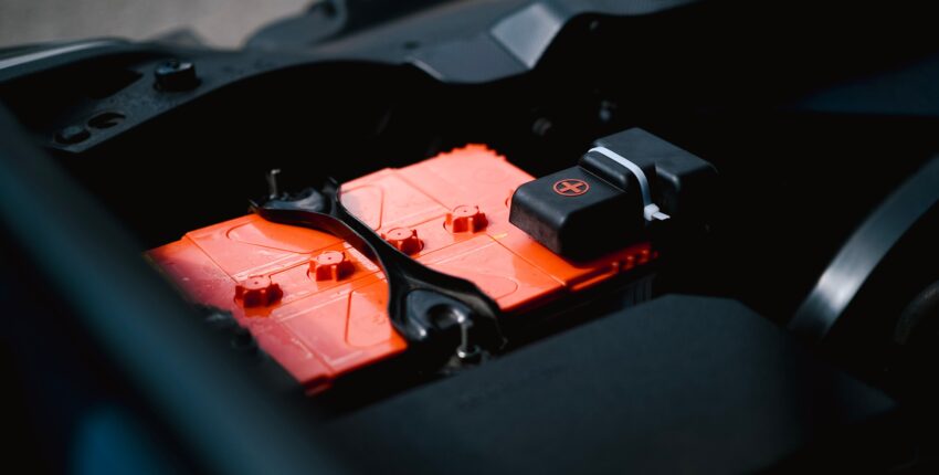 Car battery with red and black terminals in engine bay.