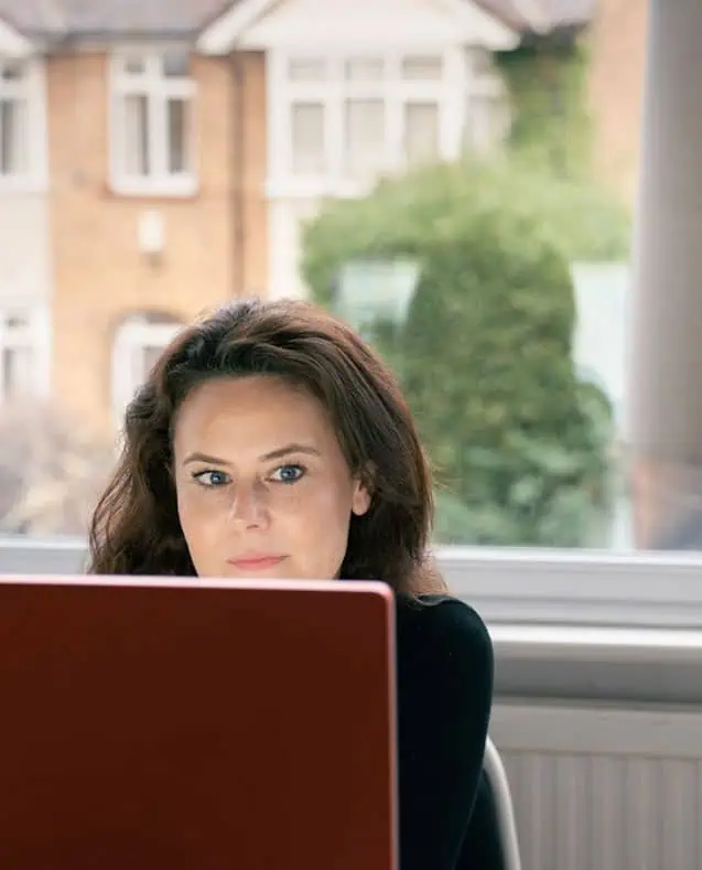 Megan working at a modern interior design workspace with large window view.