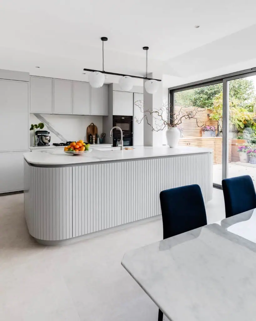 Elegant Victorian refurbishment kitchen with contemporary white cabinetry and large glass doors.