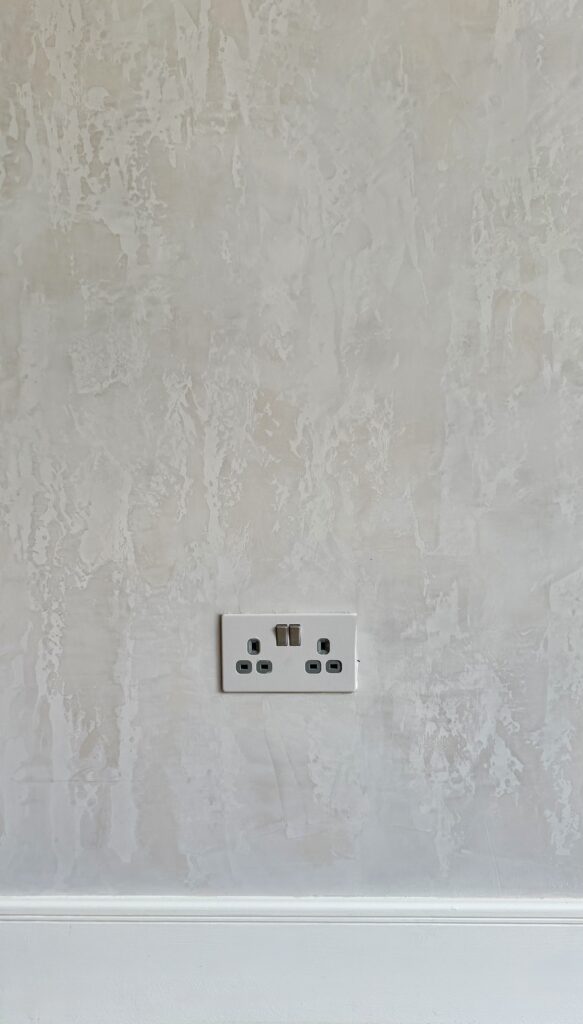 Close-up of a sleek, modern power outlet on a textured wall.