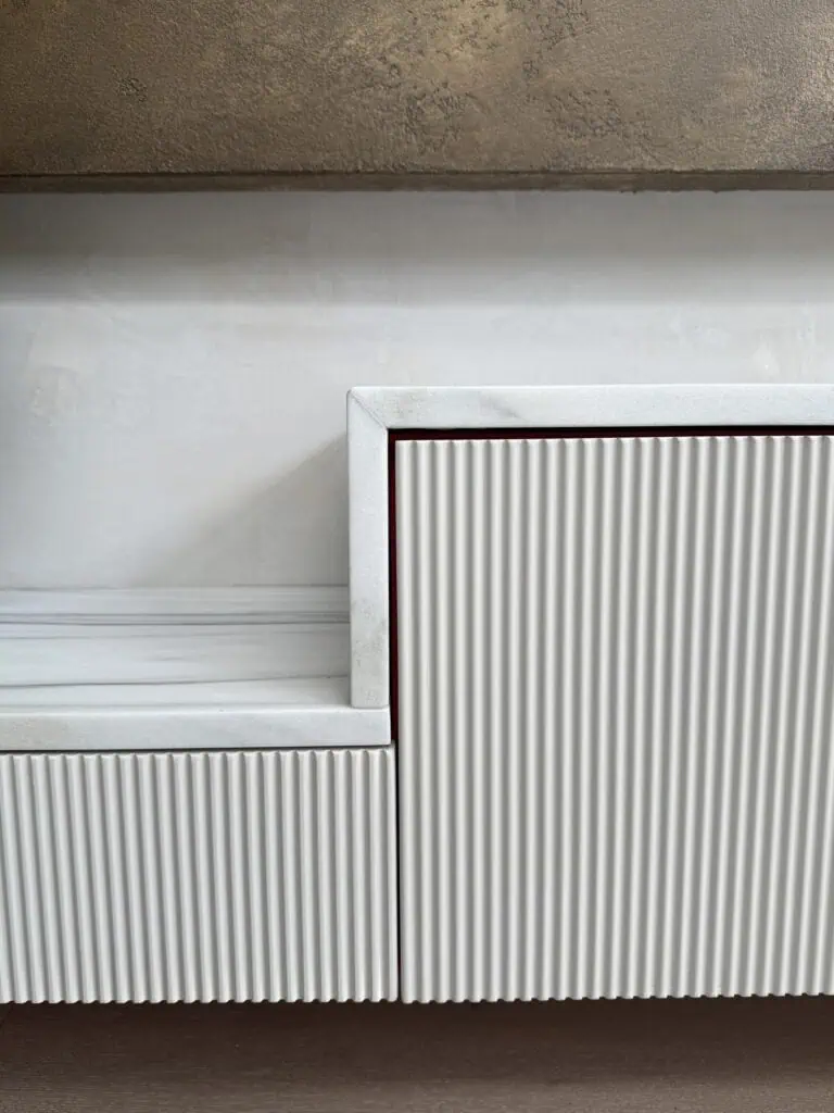Bespoke wall unit with vertical ribbed panels in a contemporary interior setting.