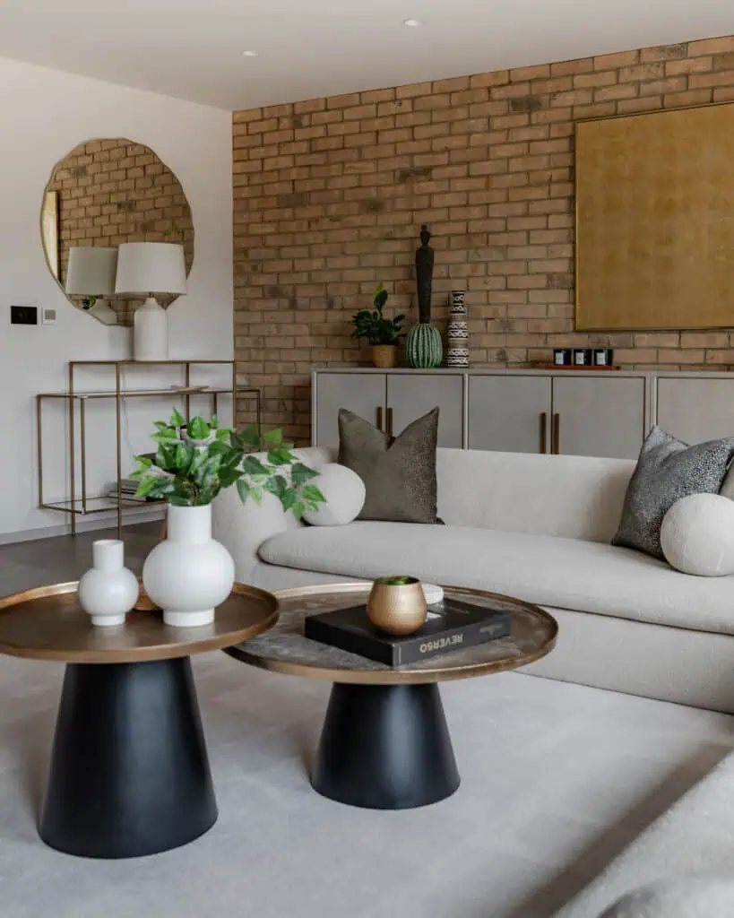 Contemporary living room featuring a brick wall, neutral sofa, and stylish decor elements.