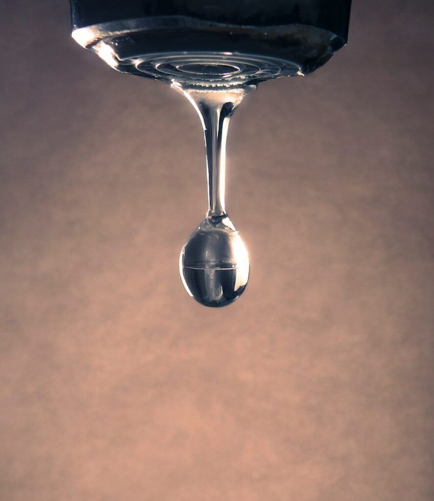 A water drop forms from a faucet. plumbing leaks