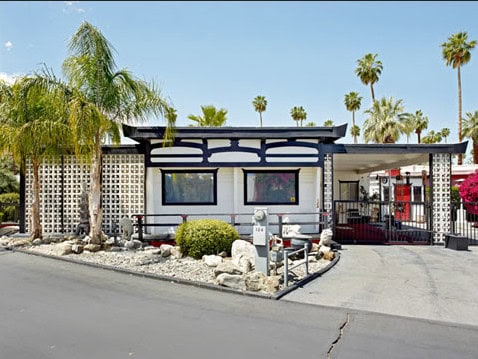 Modern mobile home with desert landscaping and palm trees in Palm Springs.