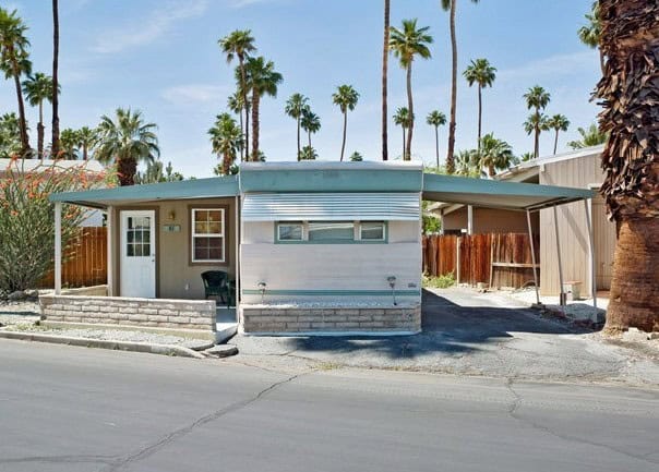 Modern mobile home with desert landscaping and palm trees in Palm Springs.