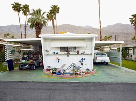 Modern mobile home with desert landscaping and palm trees in Palm Springs.