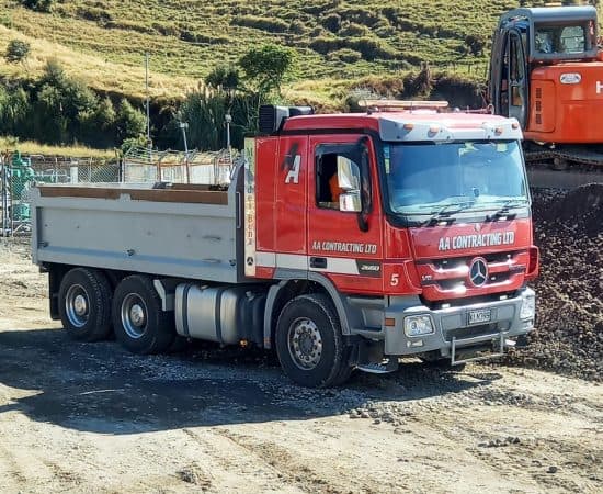 Mercedes-Benz truck on training site with construction machinery in background.