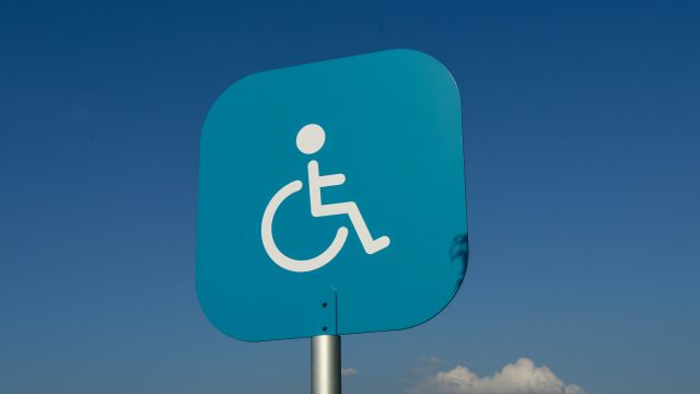 Sign above a disabled parking bay outside a supermarket in Swansea isolated against a blue sky