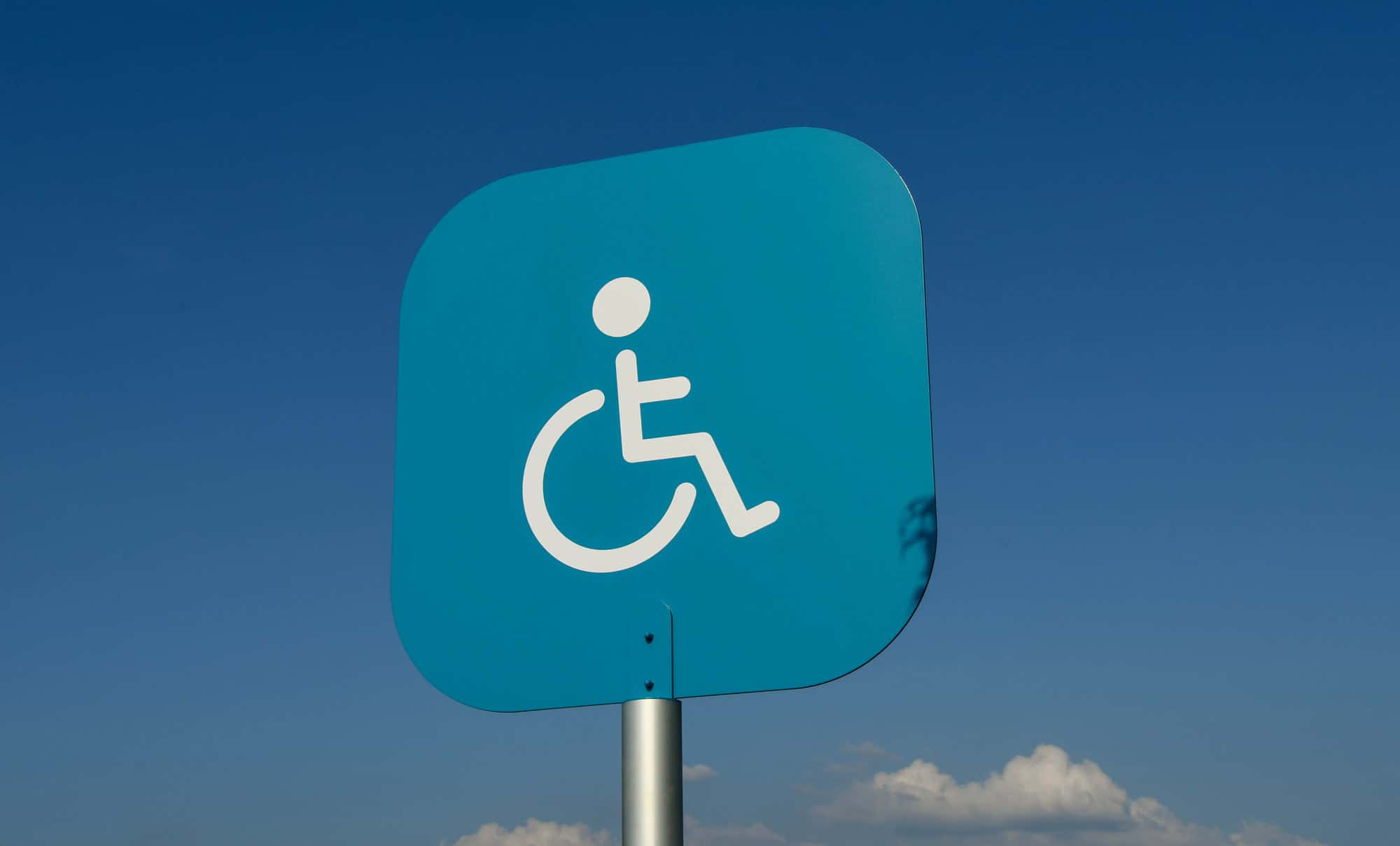 Sign above a disabled parking bay outside a supermarket in Swansea isolated against a blue sky