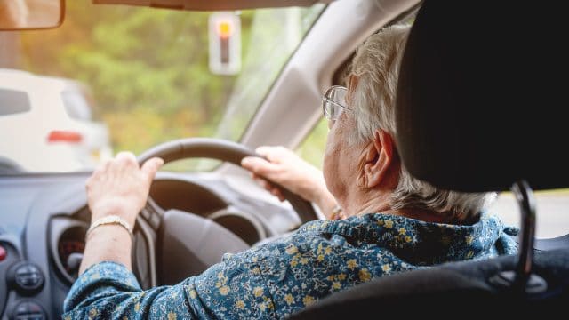 Cheerful senior woman driving a car. Old lady in glasses drive the car in glasses.