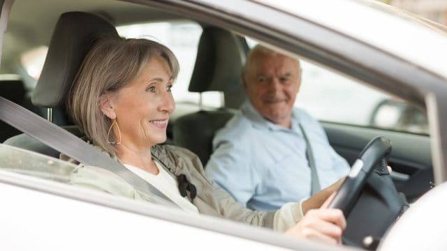 Mature couple sitting in car. Woman sitting at driver's seat.