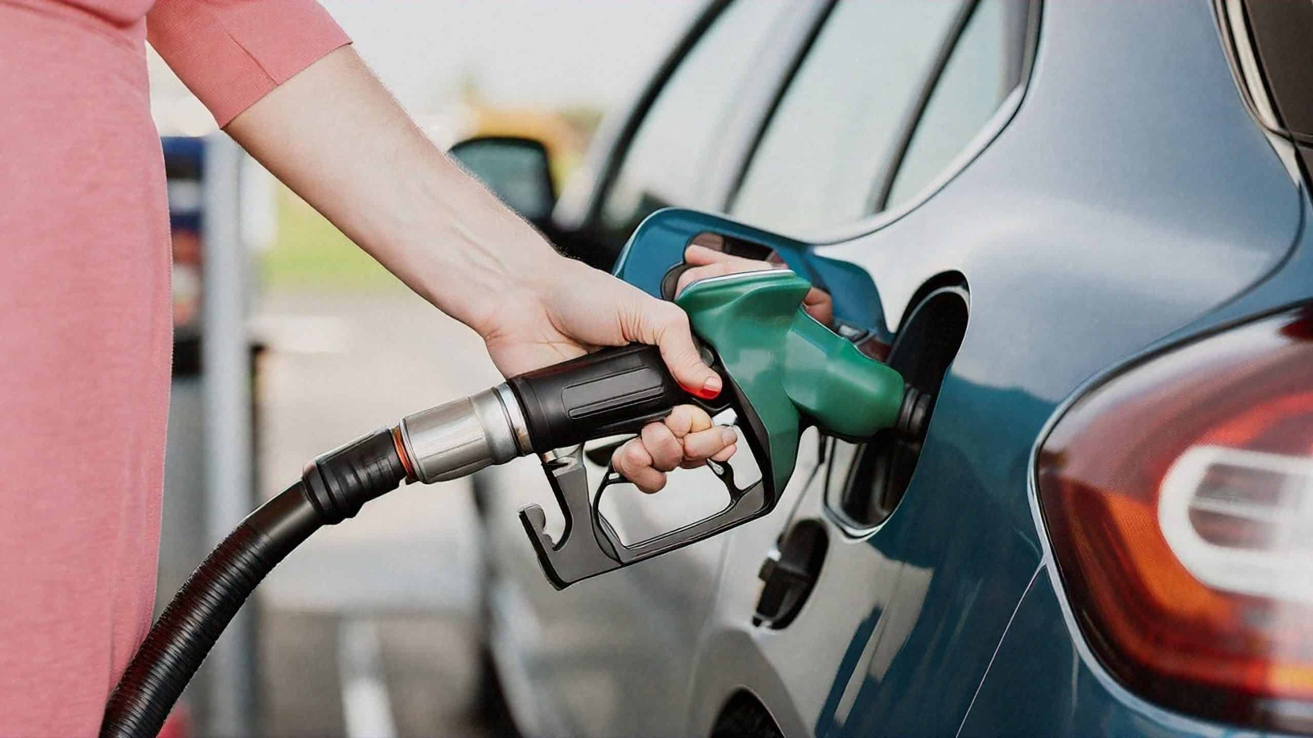 Close up of hand filling up car with fuel at a UK fuel station.