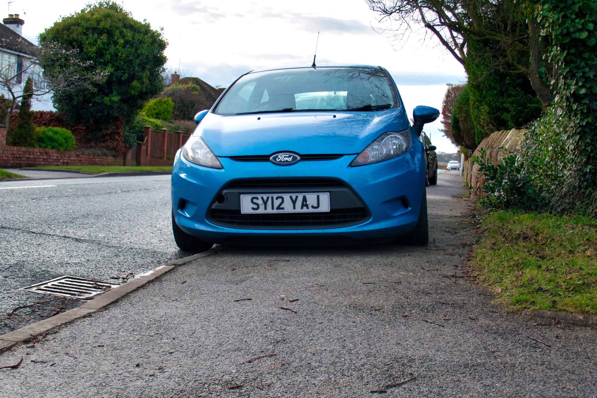 A car parks on the pavement, severely restricting space for pedestrians