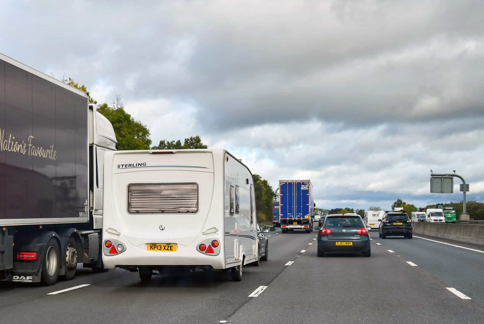Car towing a caravan overtaking an articulated lorry on the M5 motorway