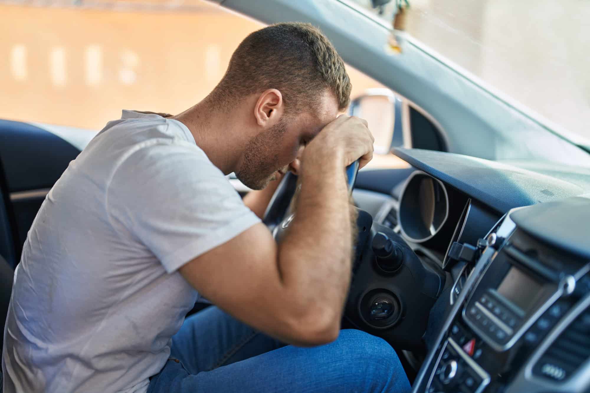 Young caucasian man stressed driving car at street