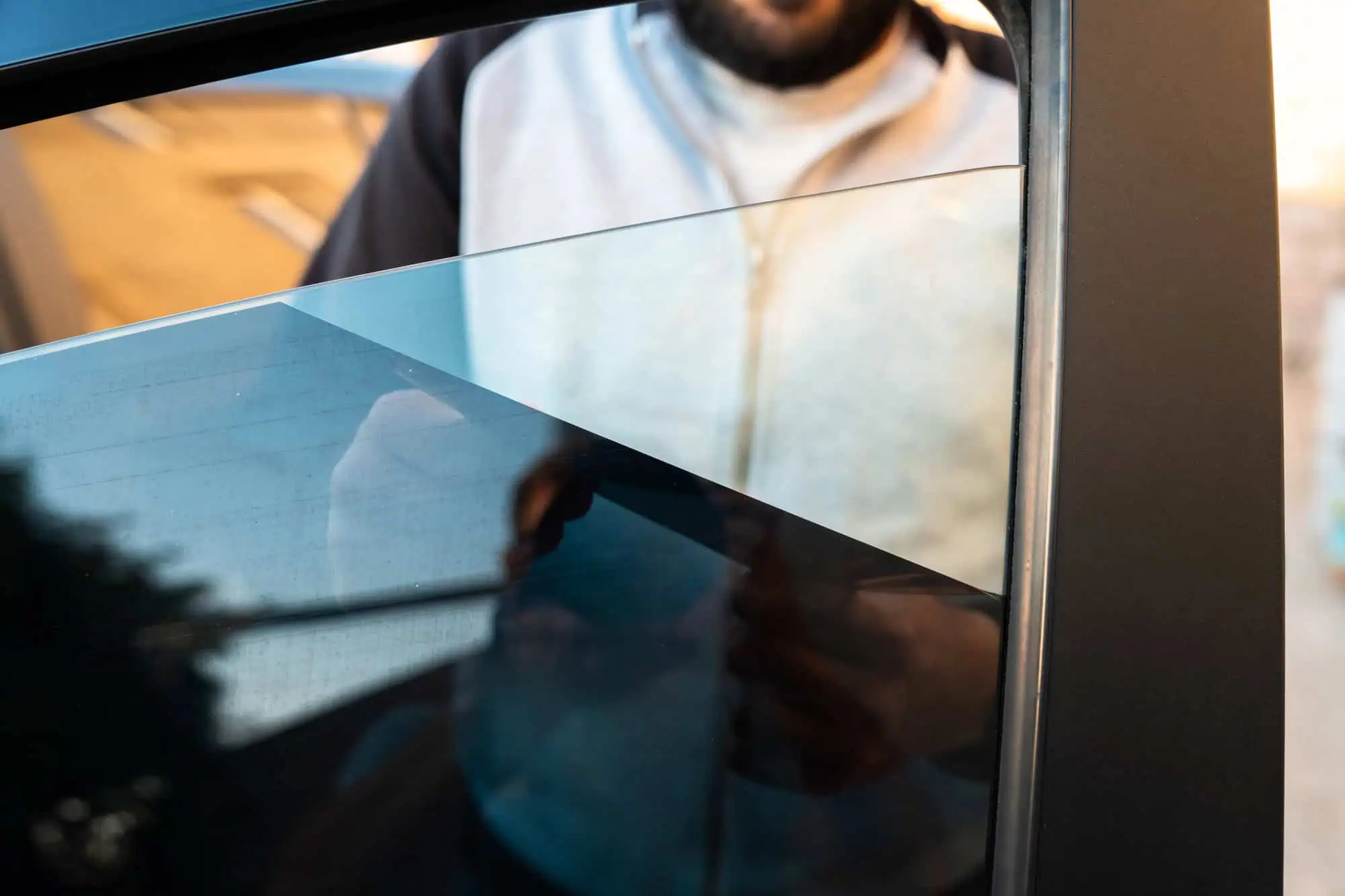 A man removes the tint from the side windows of a car