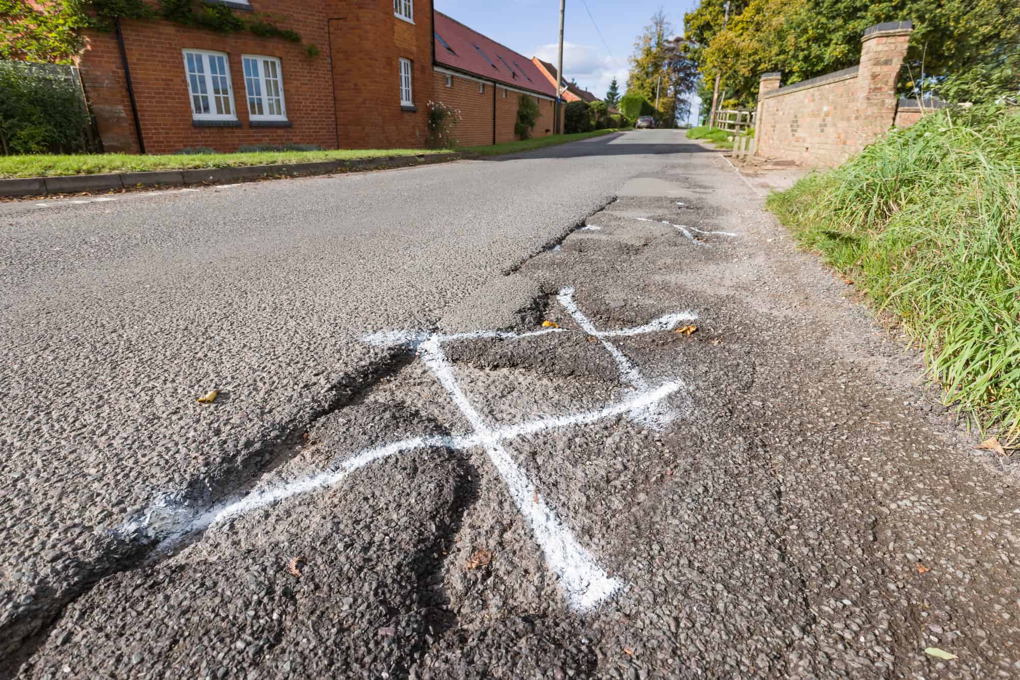 pot holes in UK country road marked for highway maintenance