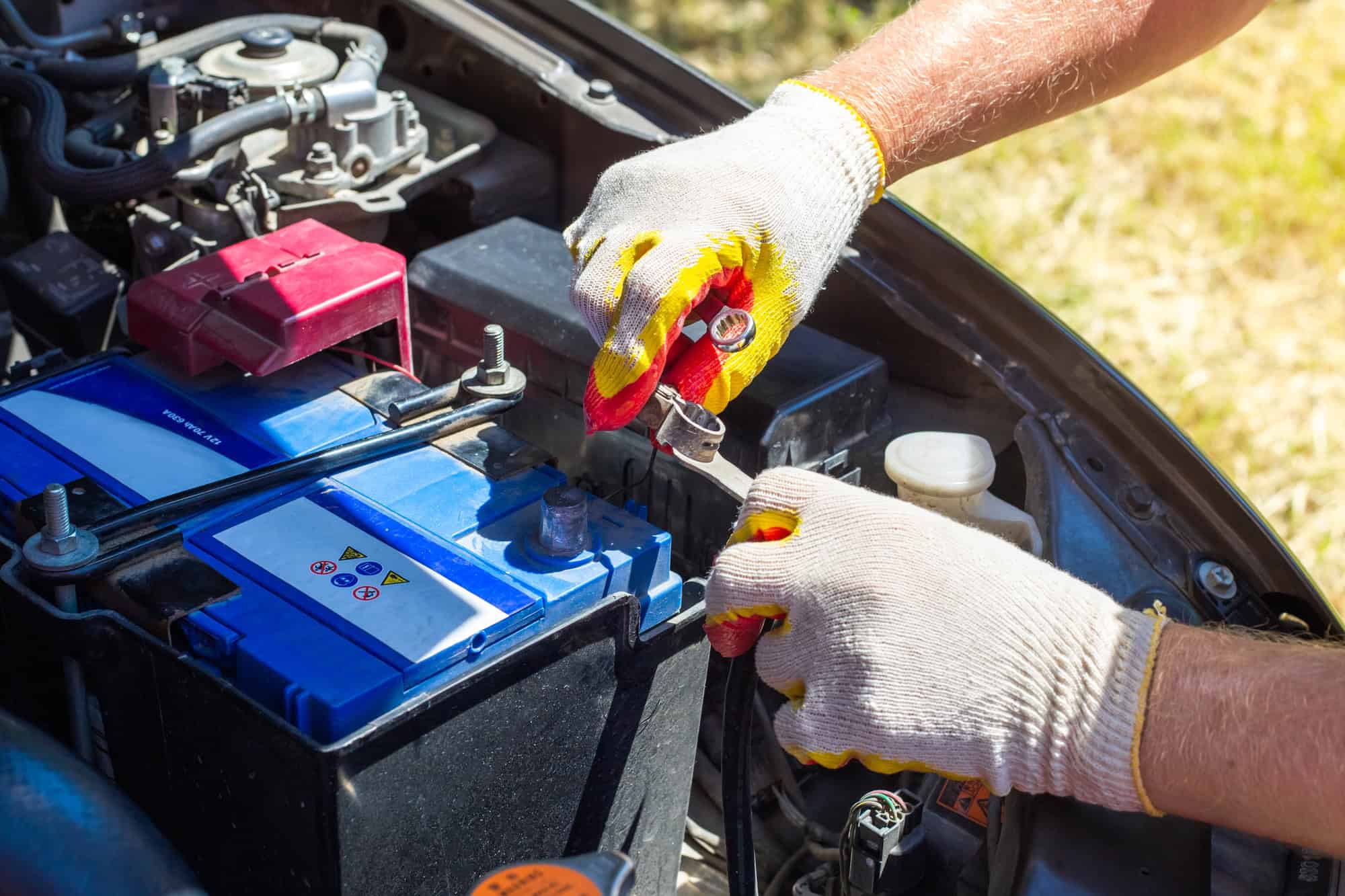 The car mechanic unscrews the car battery holder to repair or replace it.