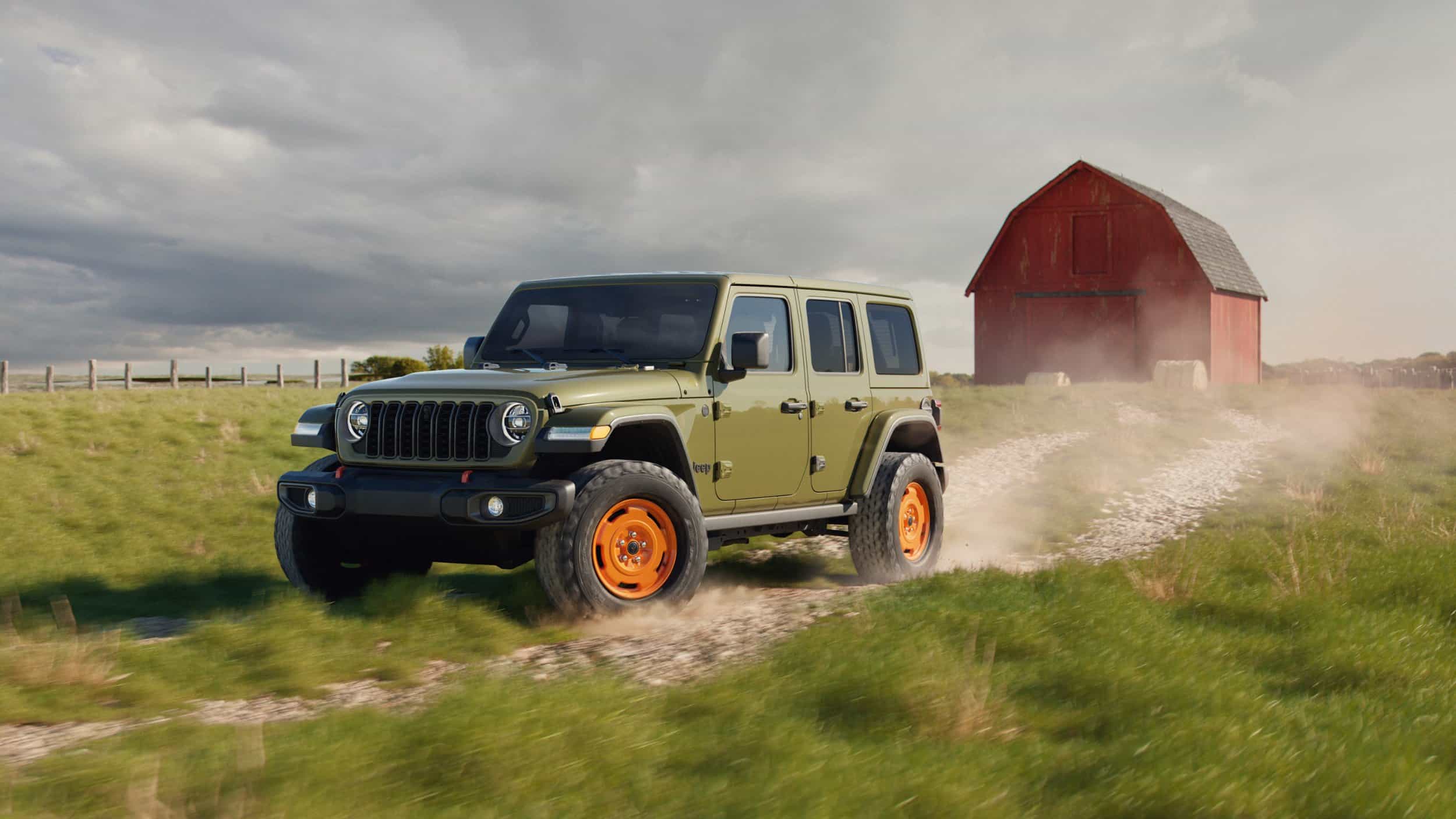2027 Jeep Wrangler JL-2A in Sarge Green driving on a gravel path near a red barn