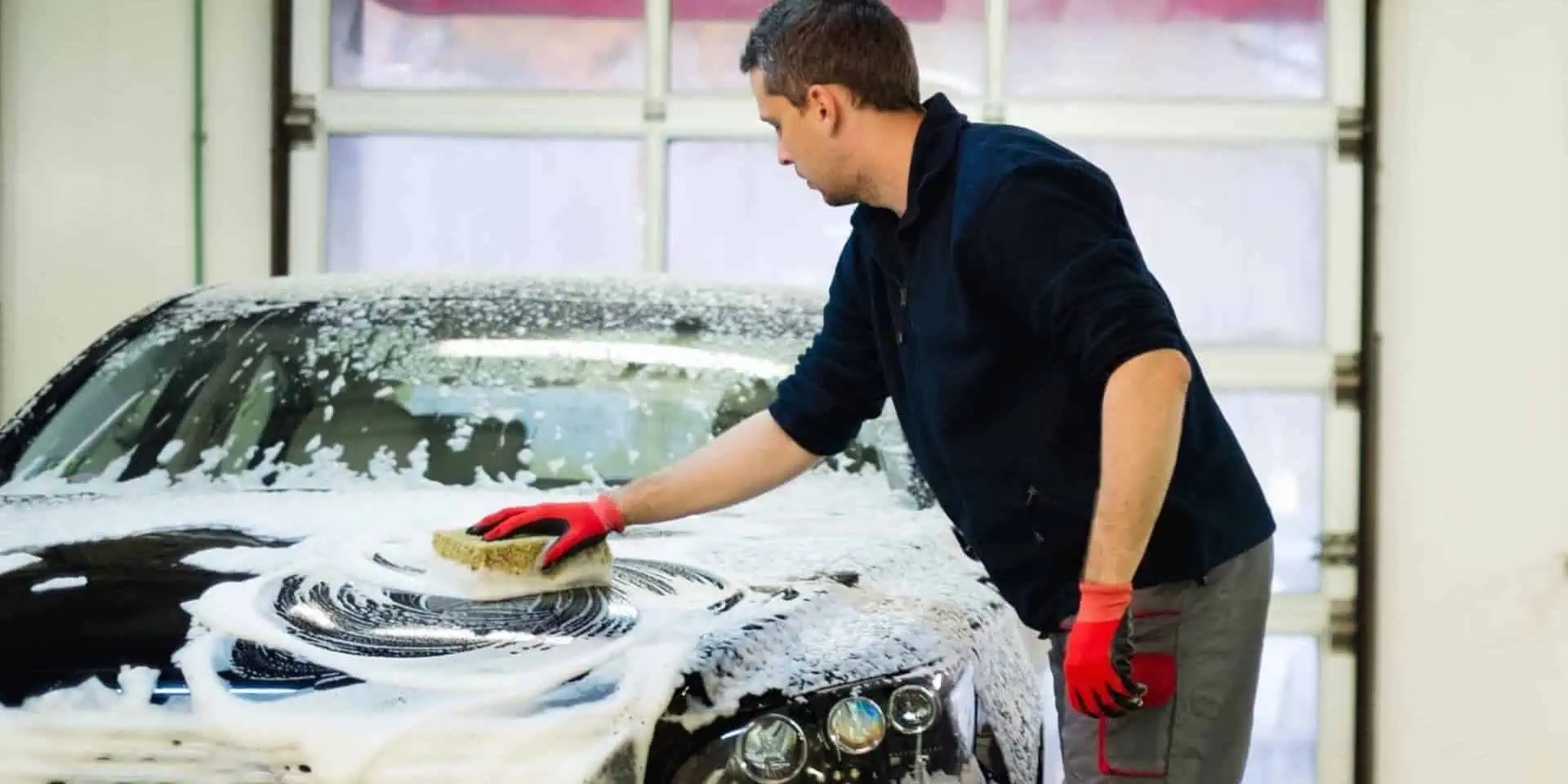 Man worker washing luxury car with sponge on a car wash