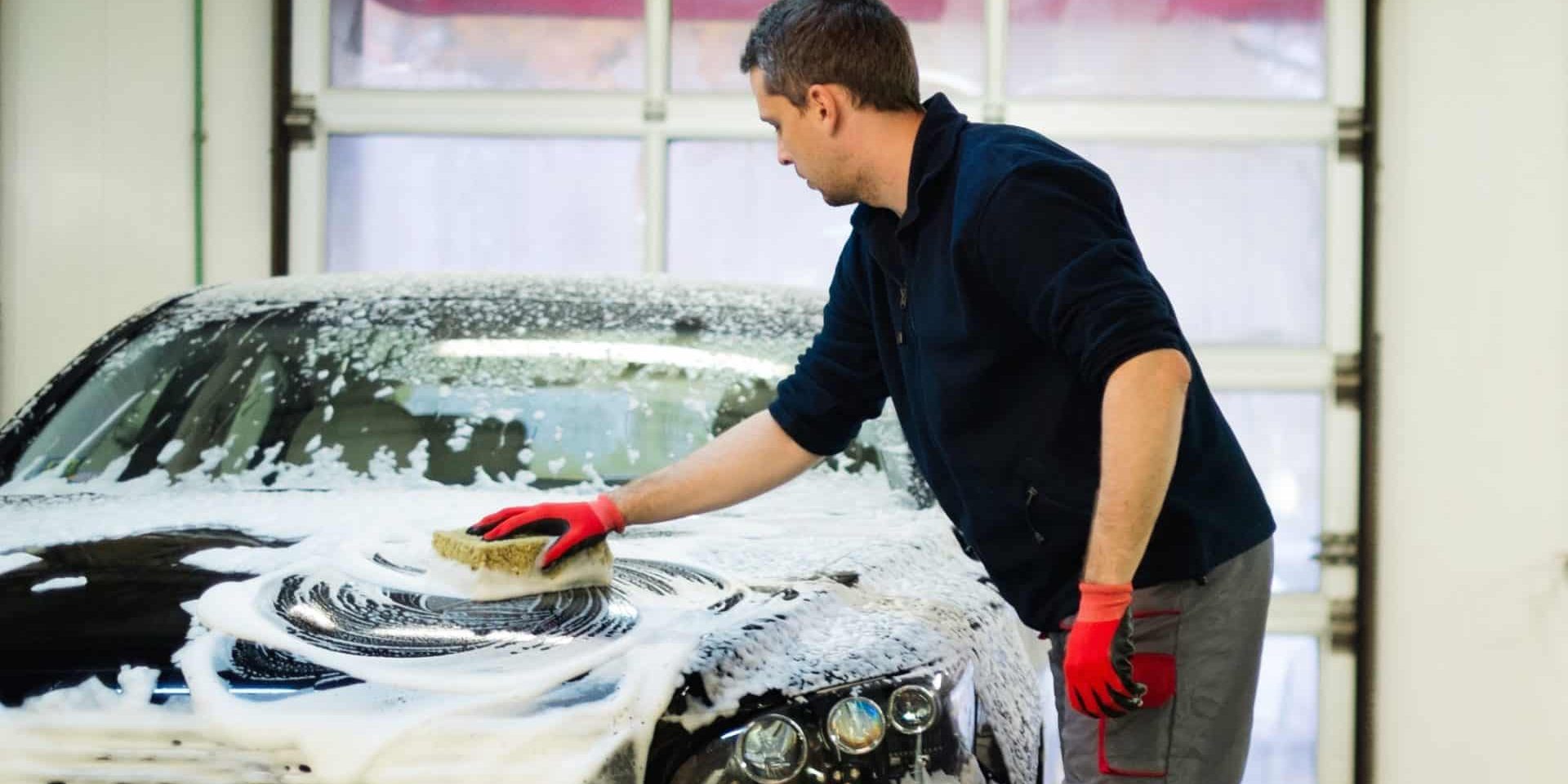 Man worker washing luxury car with sponge on a car wash