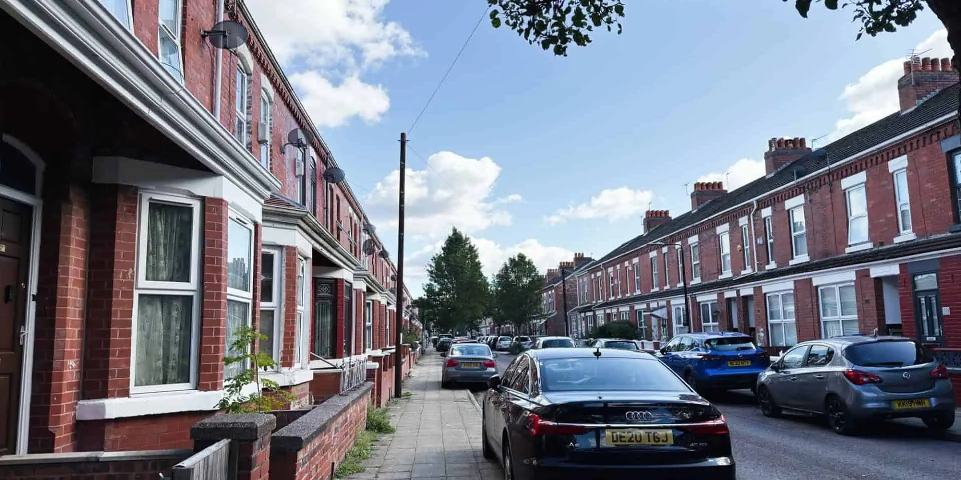 Manchester, UK - September 23, 2025: Red brick terrace houses line a residential street in Manchester, with cars parked along the curb