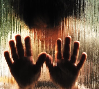 A person's hands practicing manual therapy are seen through a glass window, promoting recovery and health and wellness.