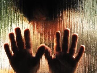 A person's hands practicing manual therapy are seen through a glass window, promoting recovery and health and wellness.