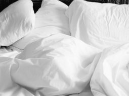 A black and white photo depicting a bed with white sheets promoting health and wellness.