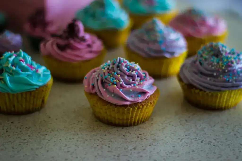 Vibrant cupcakes topped with colorful icing and sprinkles on a countertop.