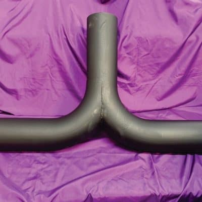 Polished custom vehicle exhaust pipe against purple fabric background.