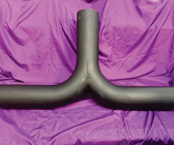 Polished custom vehicle exhaust pipe against purple fabric background.