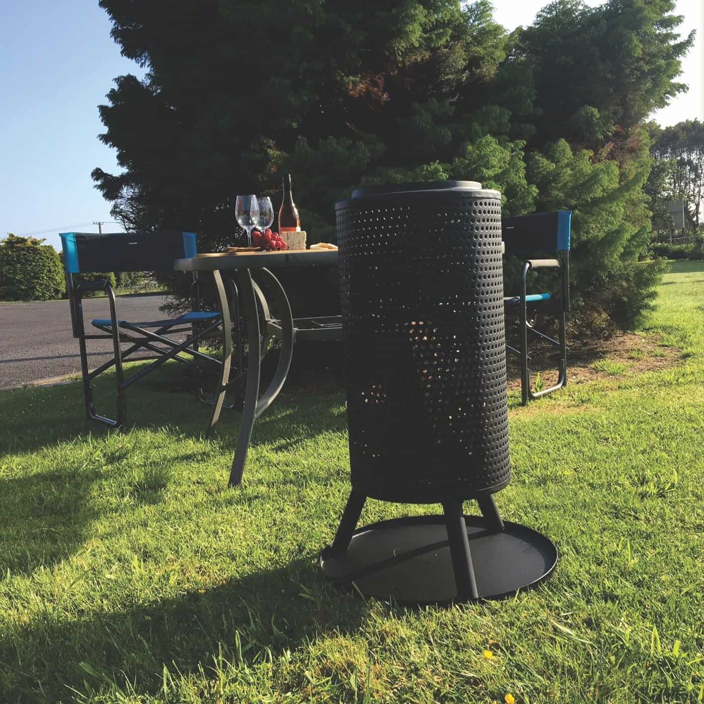 Sleek black outdoor fire pit with modern design on green grass in garden setting.