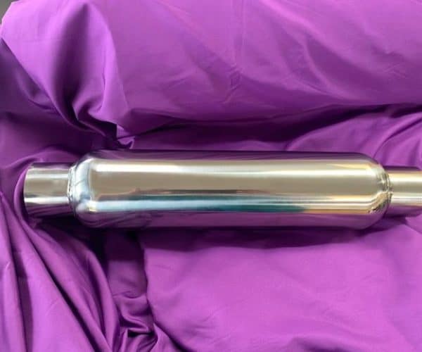 Stainless steel muffler placed on purple fabric for automotive exhaust system repair.
