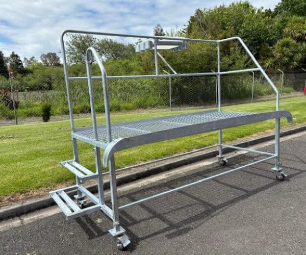 Heavy-duty stainless steel work platform with guardrails and wheels for mobility.