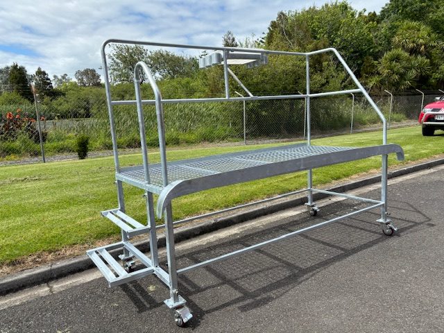 Heavy-duty stainless steel work platform with guardrails and wheels for mobility.