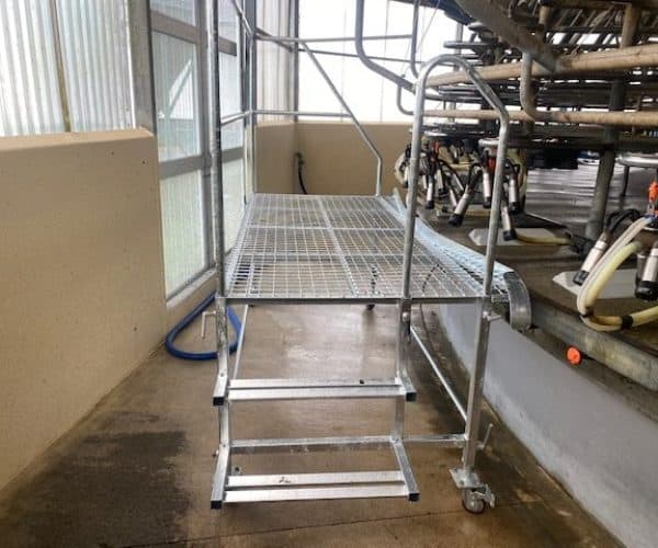 Metal rolling scaffold for muffler installation and servicing in workshop setting.