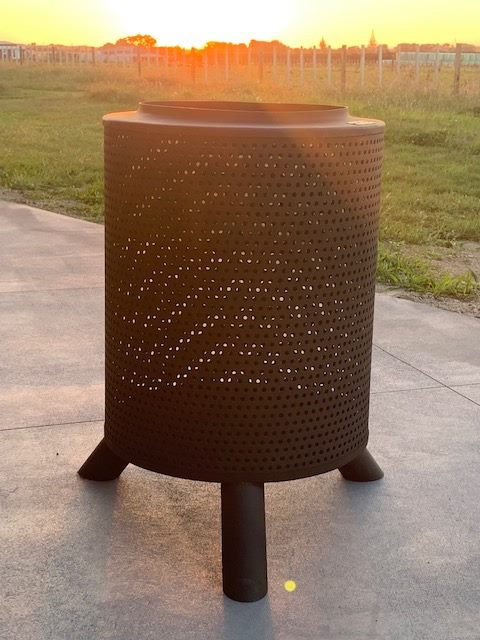Vintage style perforated fire pit or outdoor heater with tripod legs for garden gatherings.