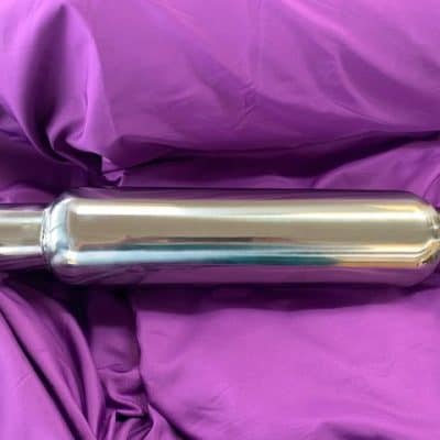 Stainless steel muffler for vehicle exhaust system on purple fabric background.