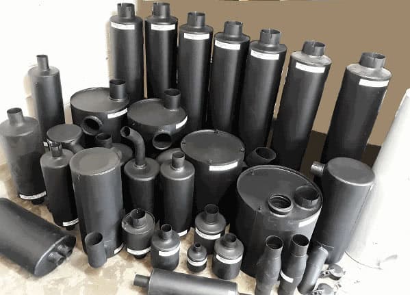 Steel muffler and exhaust part collection for vehicles in a workshop.