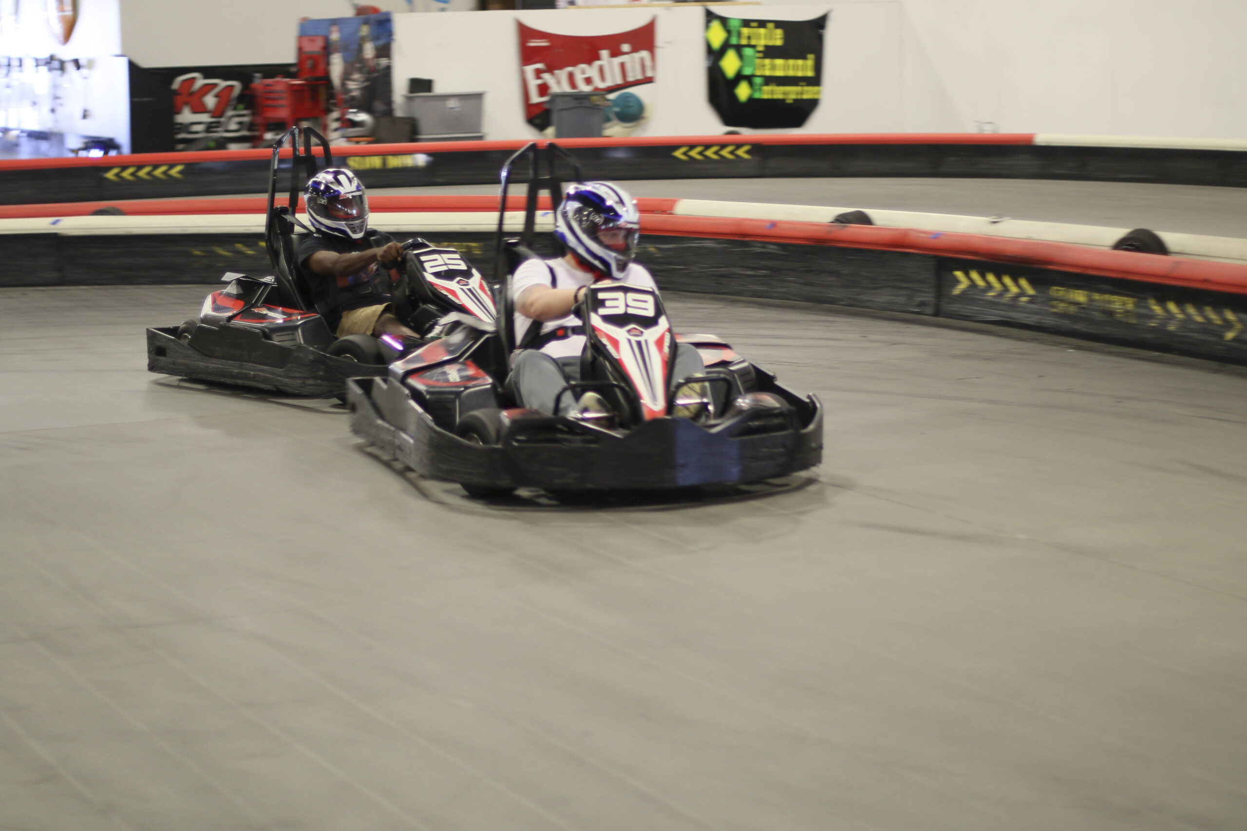 Two racers in go-karts competing on an indoor track at Mustang Week event.