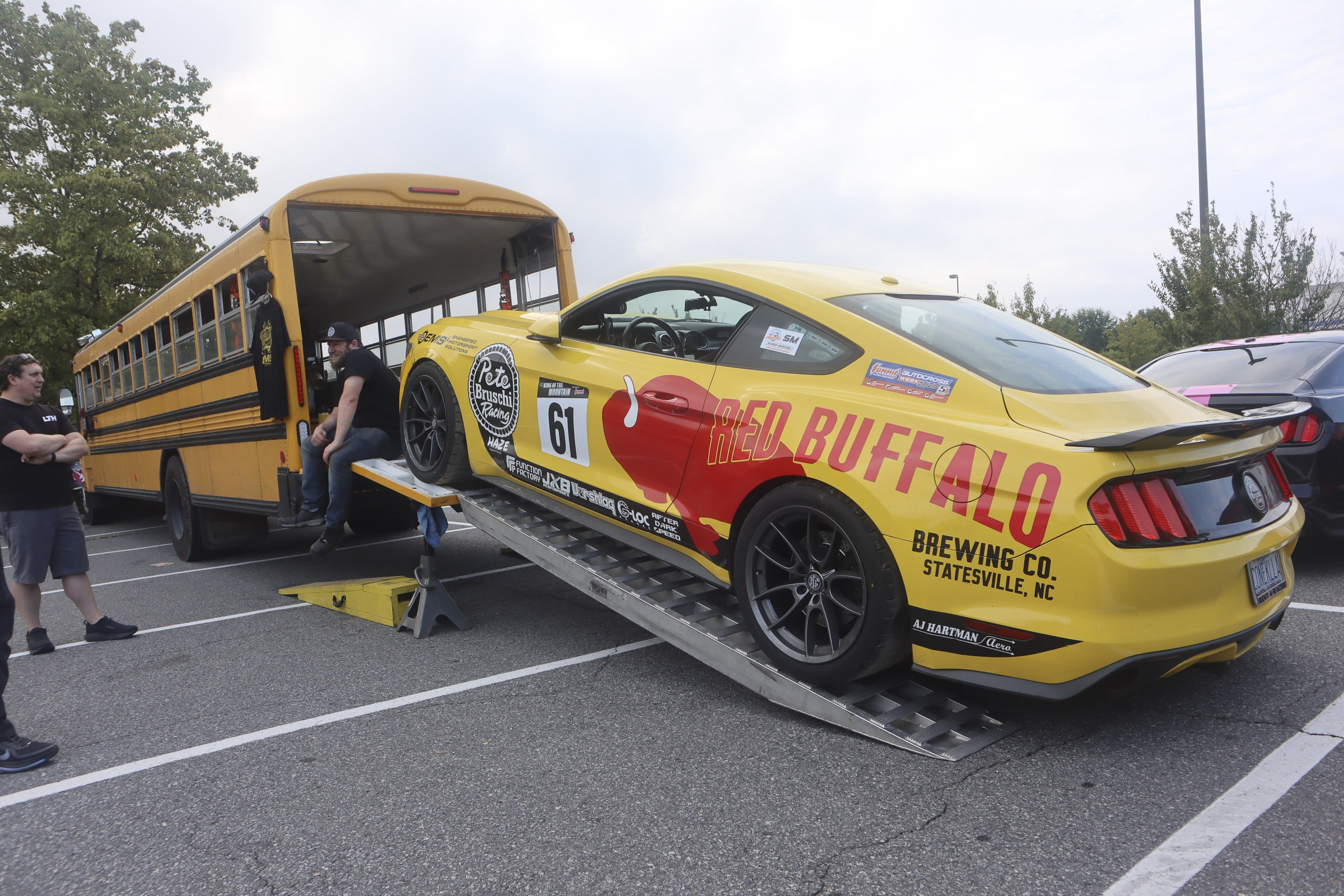 Yellow Mustang race car with Red Buffalo logo on a trailer at Charlotte 2026 event.