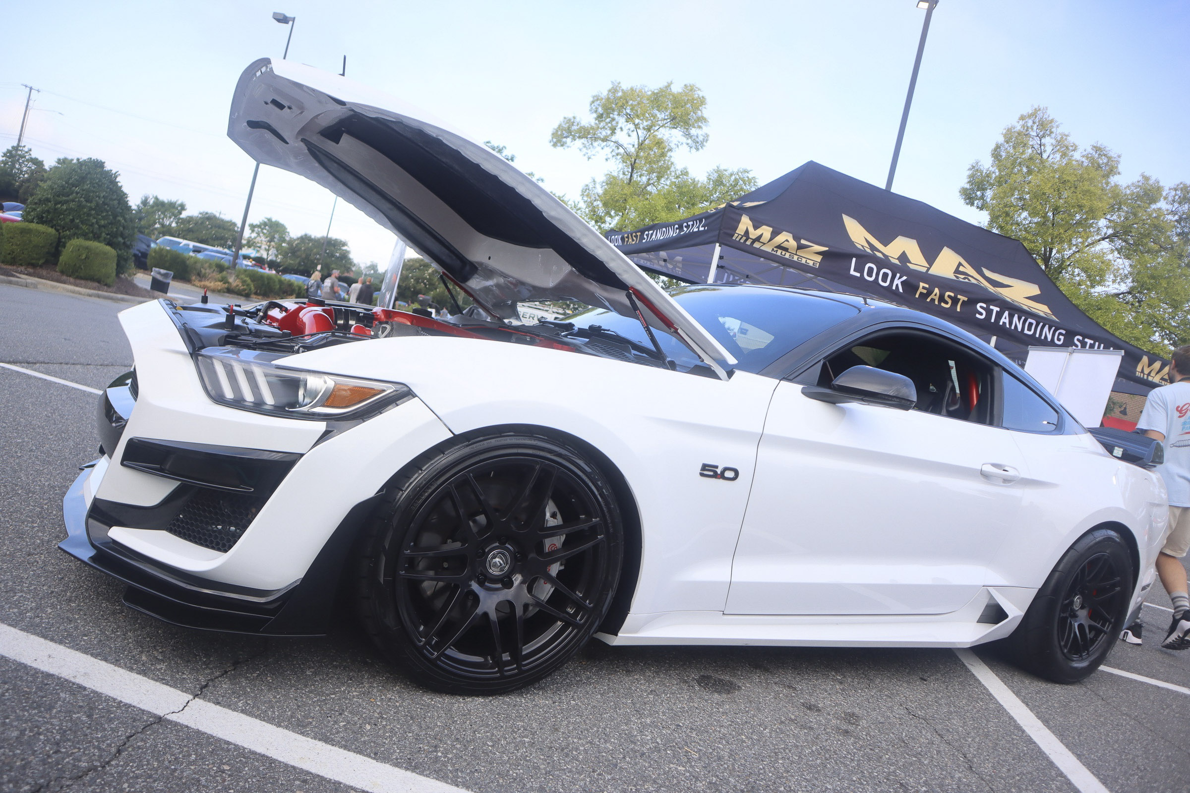 White Ford Mustang with open hood at Mustang Week event.
