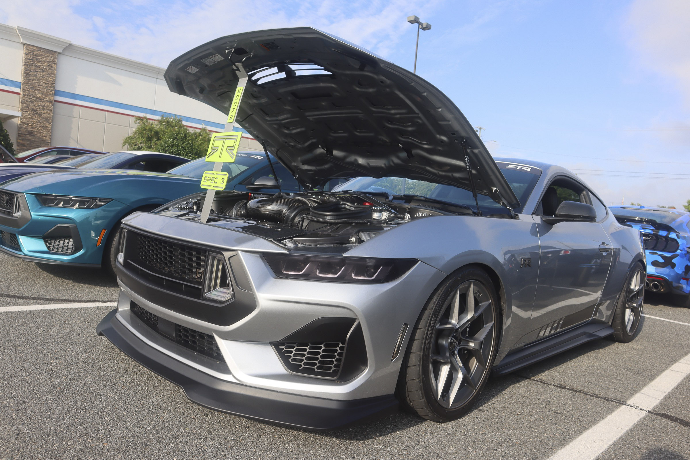 Silver Ford Mustang with open hood at Mustang Week event.